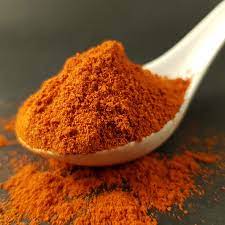 A wooden spoon filled with cayenne pepper.
