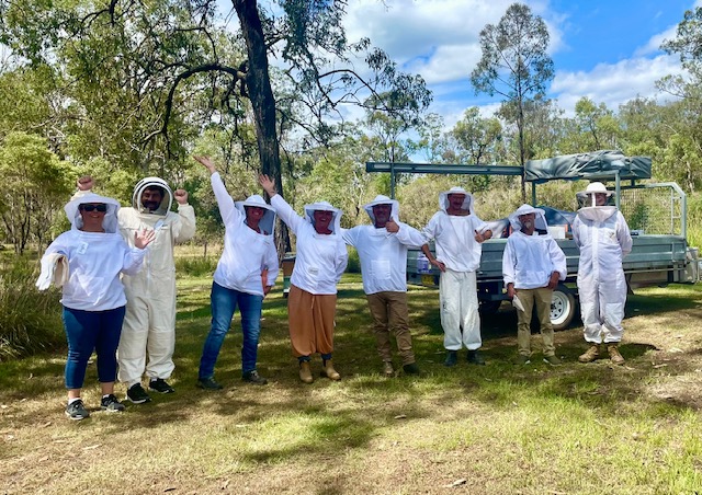 Beekeeping Basics workshop participants wearing protective beekeeping suits together outdoors