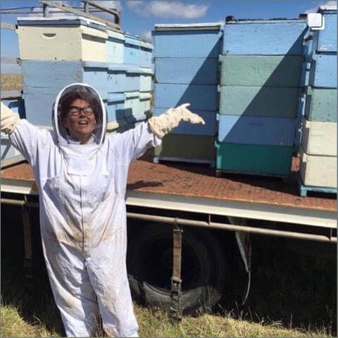 A beekeeper celebrating beside colourful hives on the apiary truck